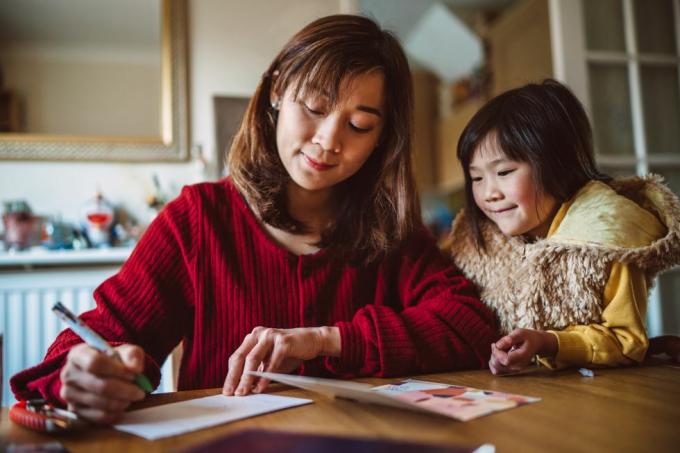 ung smuk mor skriver lykønskningskort til familie med sin dejlige datter derhjemme