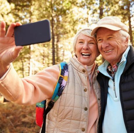 Ældre par på vandretur i en skov og tager en selfie