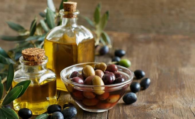 Olivenolie og oliven på træ baggrund