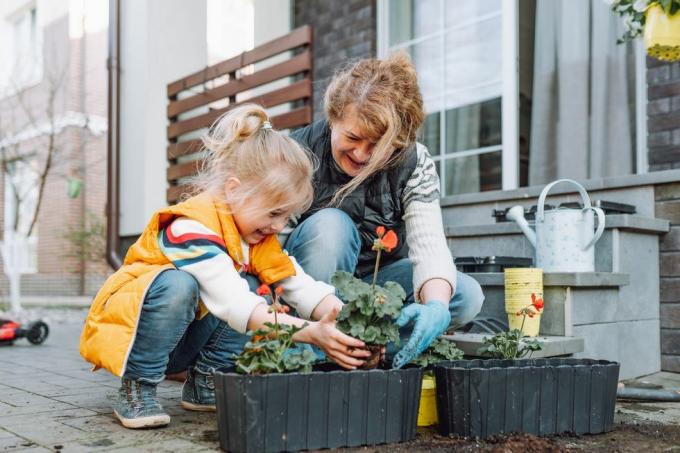 bedstemor med lille barnebarn potter blomster på en veranda om foråret