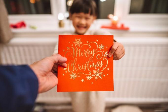 personligt perspektiv af en far, der modtager et julekort givet af hendes dejlige muntre datter i julen derhjemme koncept for julefejring med familien derhjemme