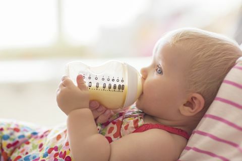 Baby pige, der drikker fra flaske på sofaen