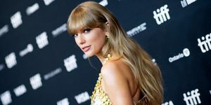 taylor swift kigger over skulderen på rød løber i guldkjole