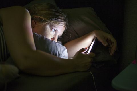 Kvinde ser på smart telefon i sengen