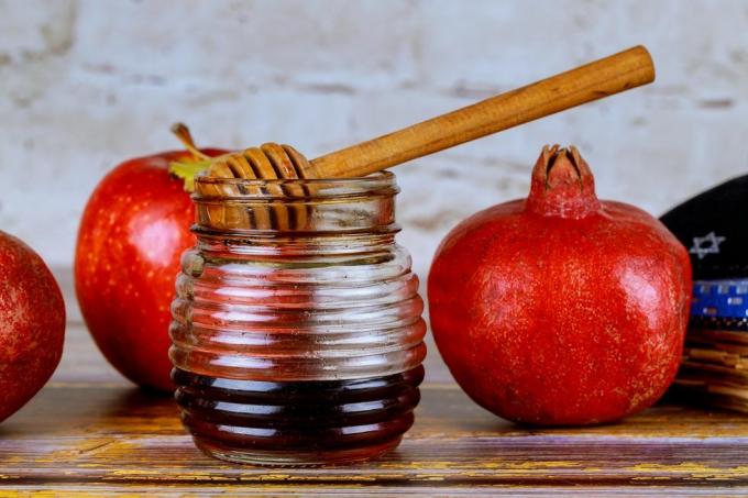 hælde honning på æble og granatæble med honning symboler på jødisk nytår rosh hashanah