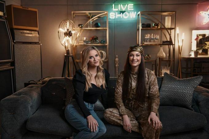 reese witherspoon og kacey musgraves siddende ved siden af ​​hinanden på sofaen