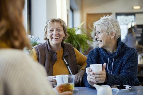 lesbisk par og voksen datter drikker kaffe og taler i cafe