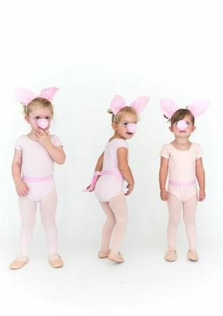 små piger i lyserøde strømpebukser og onesies med svineører og grise snuder