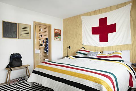 boligejer raili clasen soveværelse med stribet quilt og stort rødt kryds flag