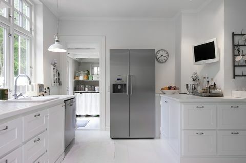 Hvidt køkken med sølvopretstående køleskab i Hanne Davidsen boligrenovering, Silkesborg, Danmark.