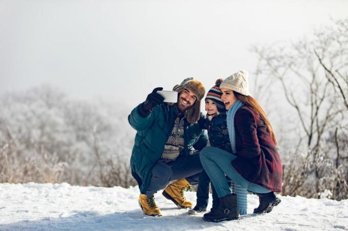 familie tager selfie på vinterdag i den sneklædte skov