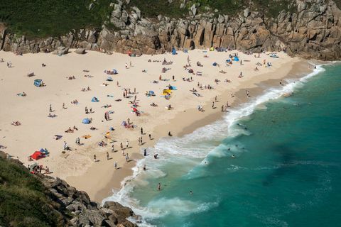 Besøgende opsuge solen på Porthcurno-stranden nær Penzance den 28. juni 2018.