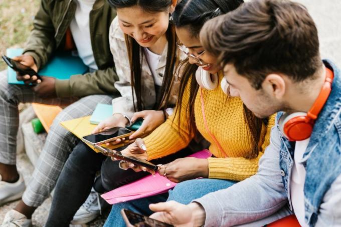 forskellige unge teenagestuderende, der har det sjovt med at bruge mobiltelefon i college campus uddannelse, millennium mennesker og sociale medier koncept