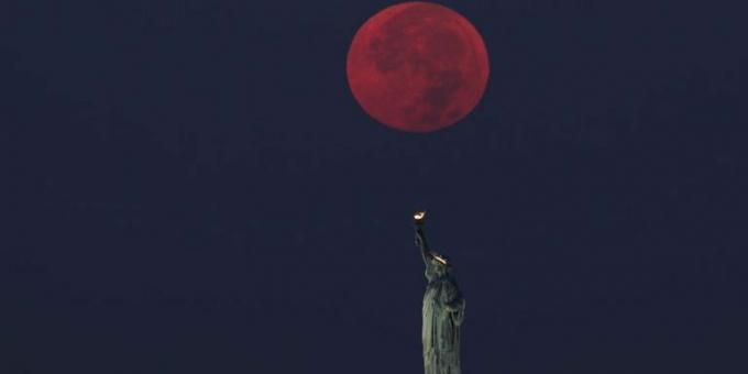 fuldmåne går ned bag frihedsgudinden i new york city